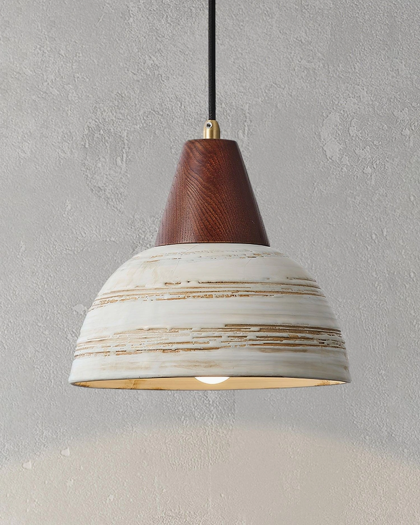 Ceramic pendant light fixture on textured concrete wall with illuminated distressed striped shade