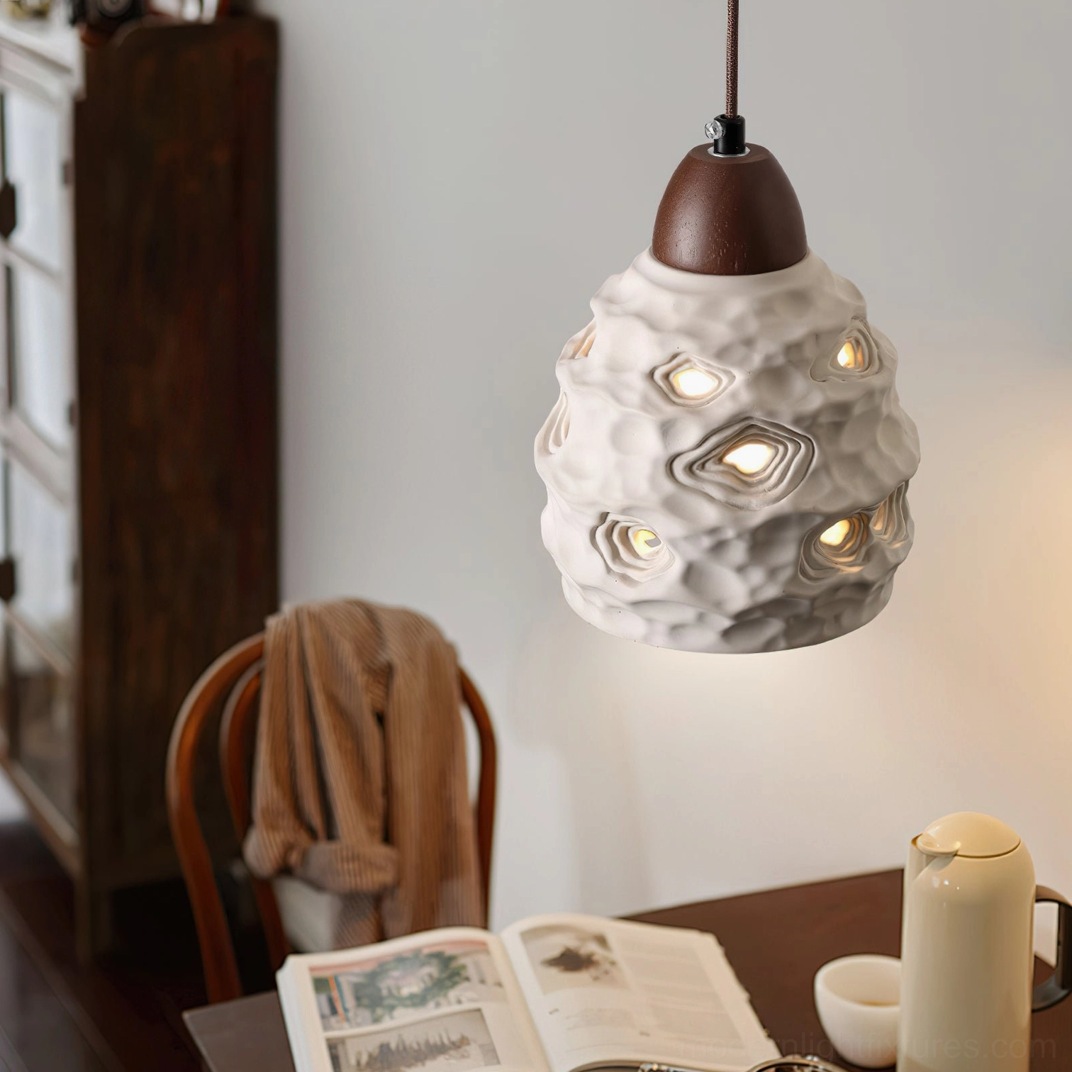 Single ceramic pendant lamp in cozy home dining space with porous off-white shade and warm ambient lighting