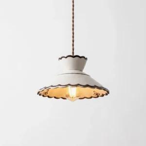 Close-up of scalloped ceramic pendant light showing cream ceramic shade, brown twisted braided cord, and warm incandescent bulb detail