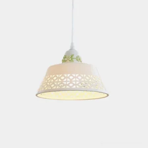 Modern ceramic pendant light with hollowed white shade and green floral accent, overhead front view with interior illumination