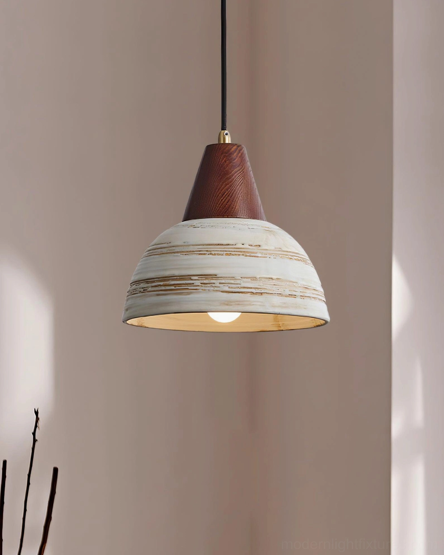 Modern ceramic pendant light with rustic distressed shade illuminated against warm neutral wall
