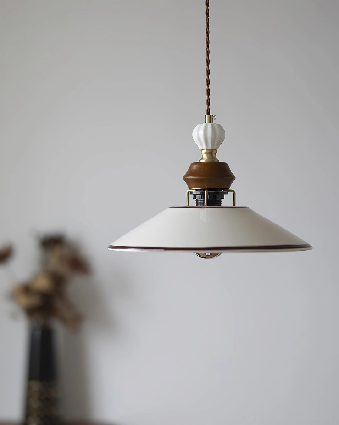 Off-white ceramic pendant light with twisted fabric cord displayed in home setting with dried flower decor, side angle view