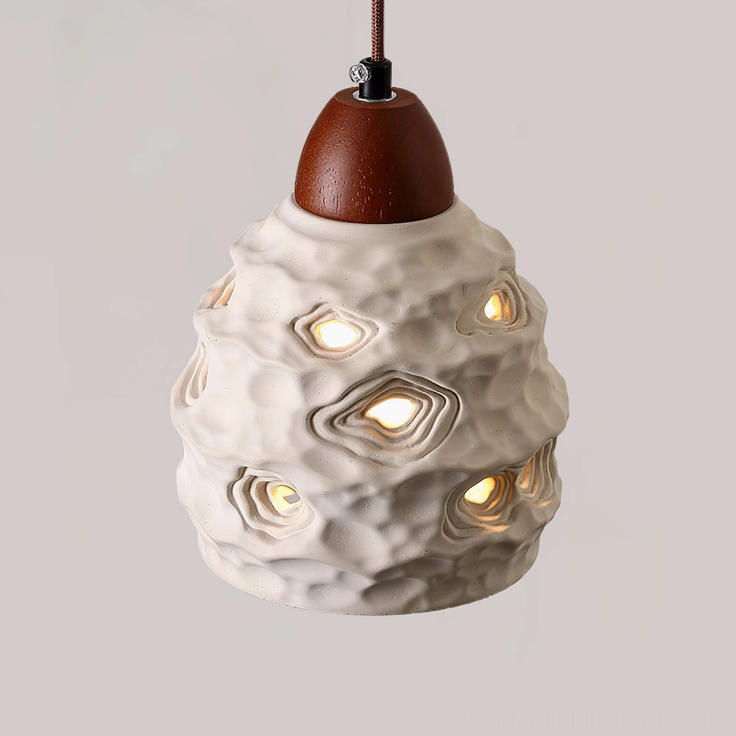 Organic ceramic pendant light showcasing perforated texture detail and sculptural walnut wood accent