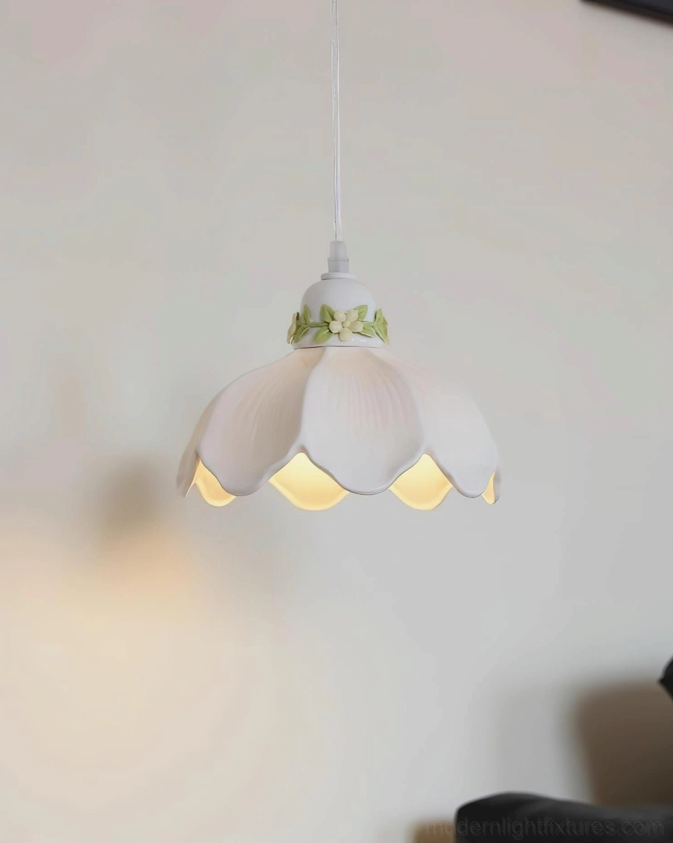 Hand-painted ceramic petal pendant light with warm glow indoors, milk white shade with botanical details, home ambiance