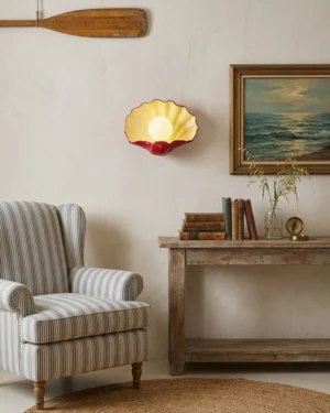 Coastal wall sconce mounted indoors with warm glowing light, vintage rustic living room setting, ceramic shell design