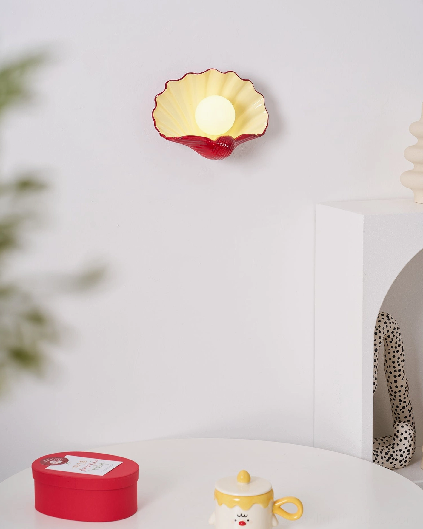 Ceramic scallop wall sconce in minimalist interior setting, contemporary coastal design, sculptural light fixture