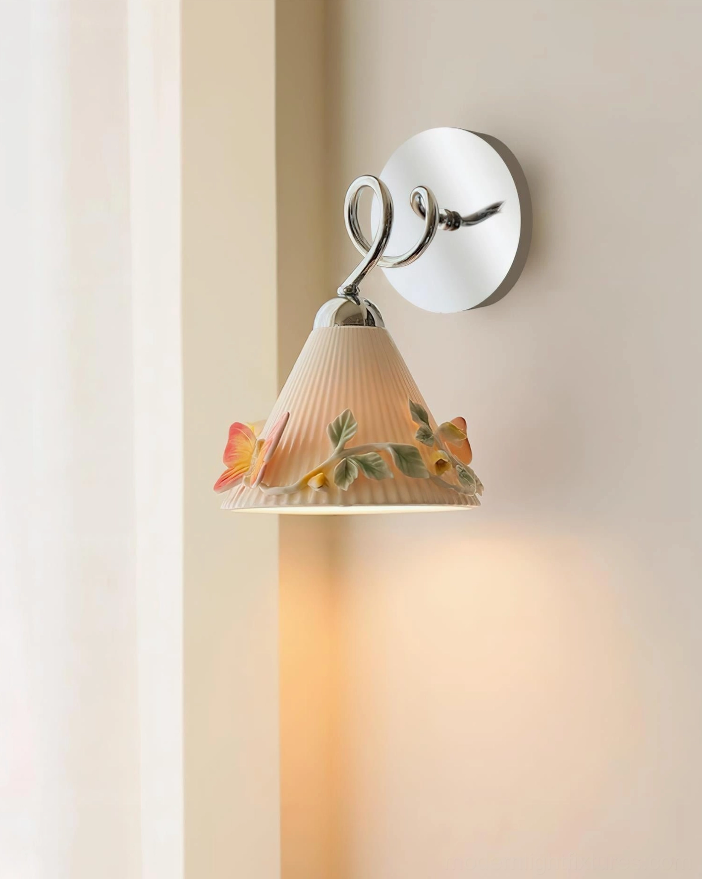 Hand-painted ceramic wall sconce side profile showing curved polished chrome metal armature and decorative embossed butterfly floral elements on neutral wall