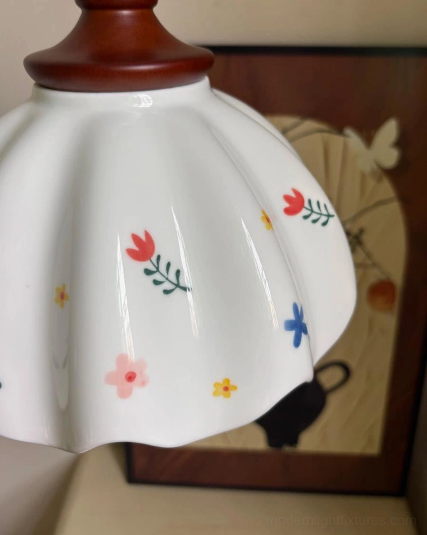Close-up overhead detail view of ceramic shade showing hand-painted colorful floral motifs on glossy white porcelain with scalloped edge