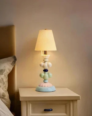 Ceramic bedside table lamp illuminated on bedroom nightstand, creating warm ambient light in cozy home setting