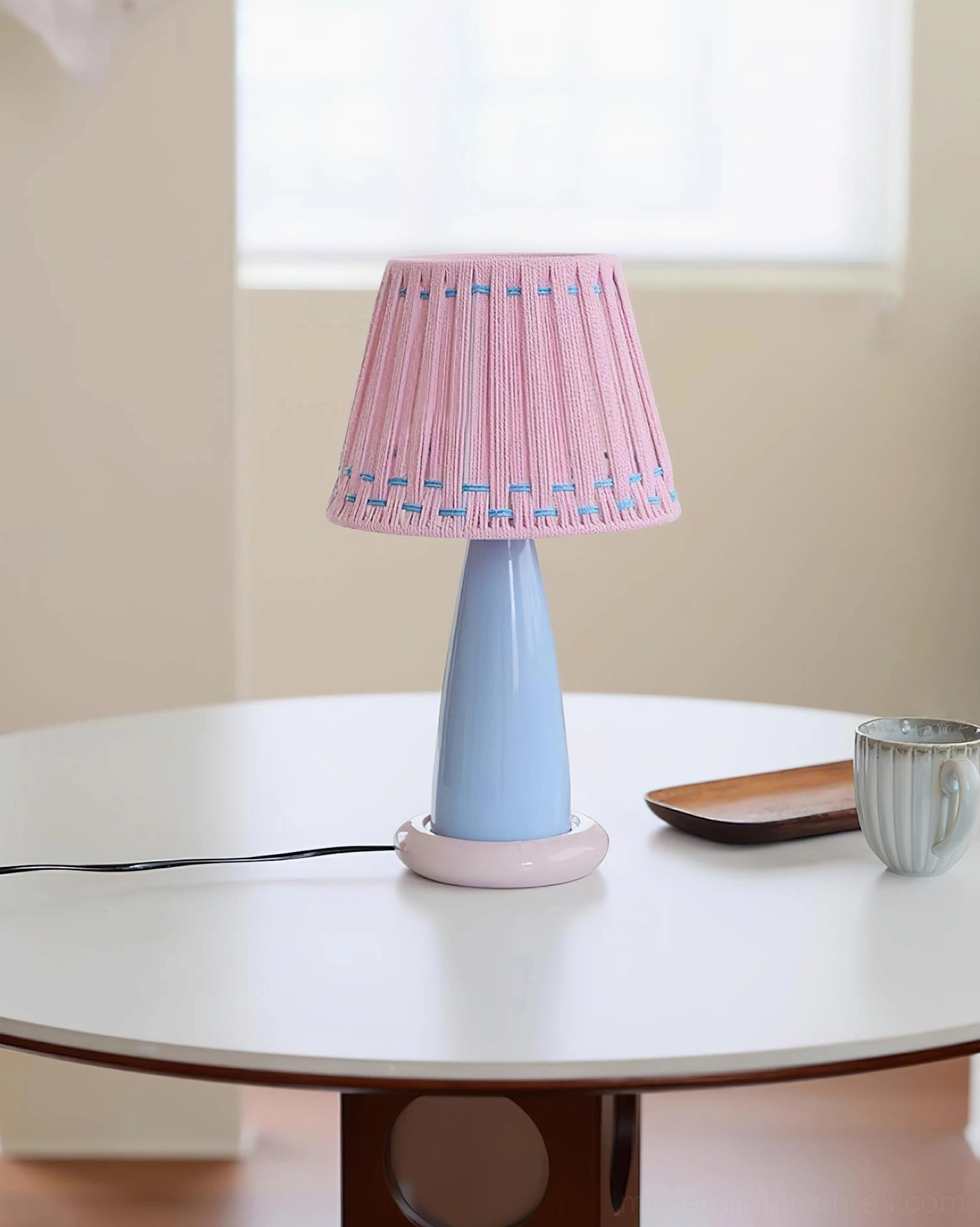 Contemporary pastel ceramic table lamp with pink woven shade on white dining table, compact modern tabletop lighting