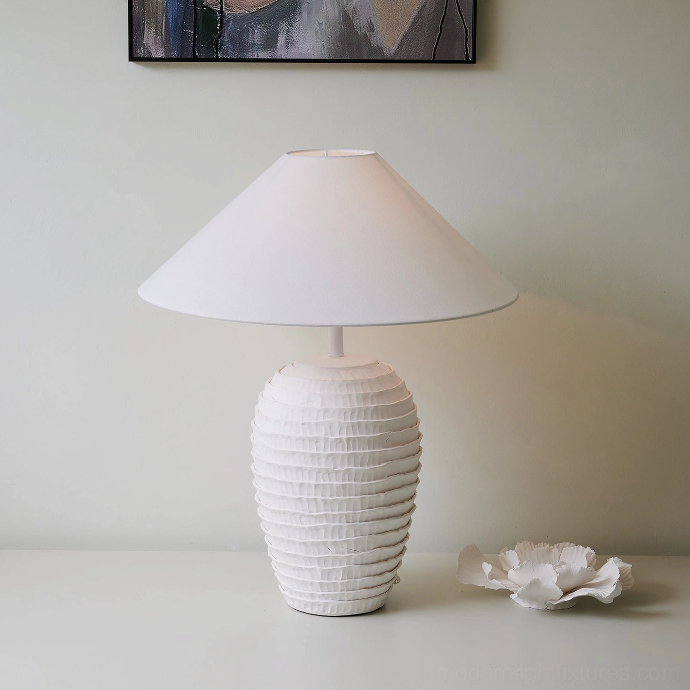 Sculptural white ceramic table lamp with pleated base texture displayed in home setting with decorative accents