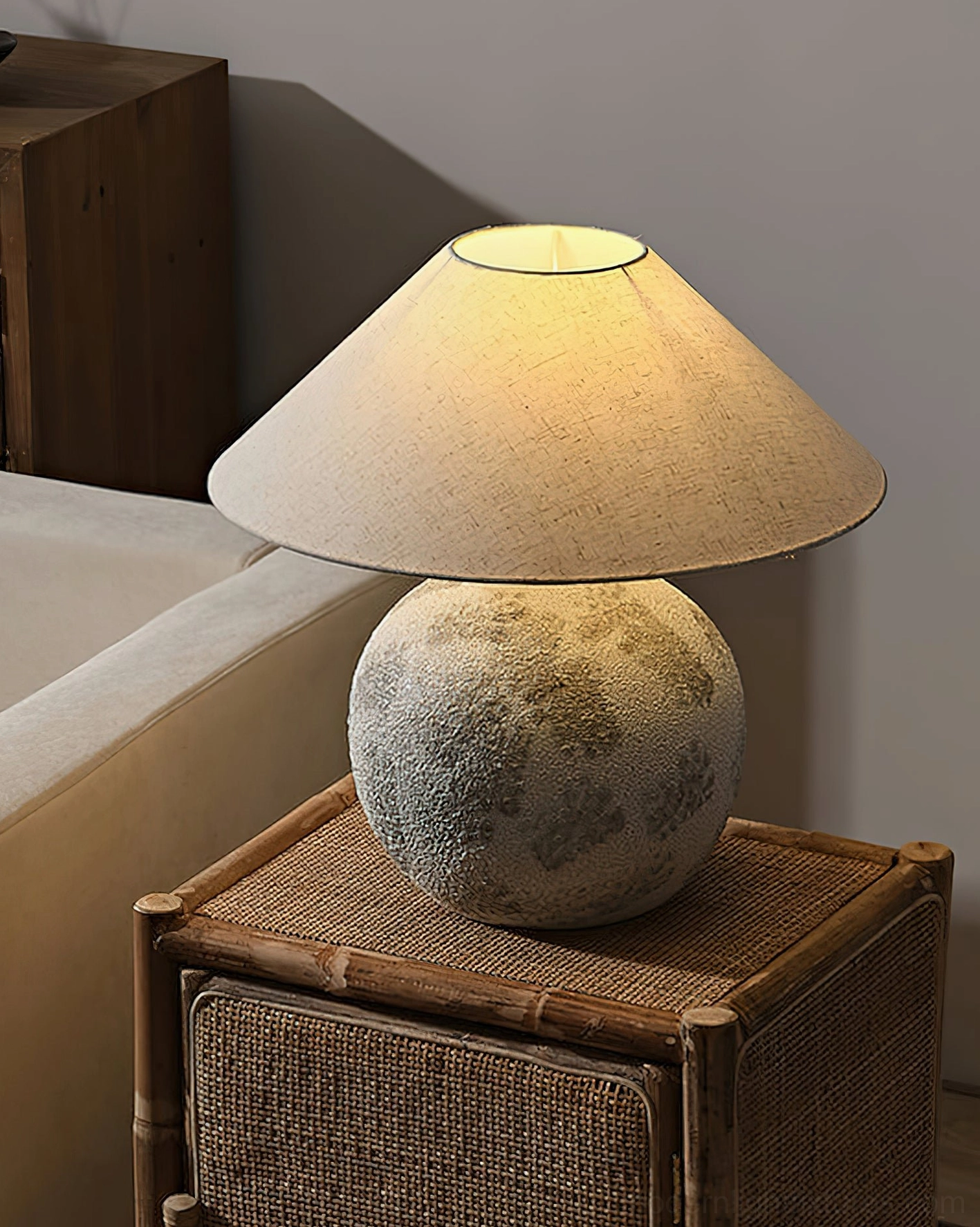 Textured ceramic table lamp on rattan side table next to fabric sofa in modern living room interior with warm ambient lighting