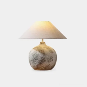 Textured ceramic table lamp with linen shade - frontal view showcasing rough ceramic base and conical natural linen lampshade with warm neutral lighting
