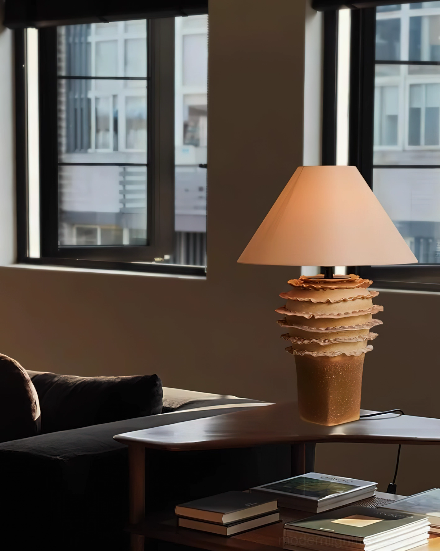 Stratified ceramic table lamp on wooden side table with stacked books in cozy living space