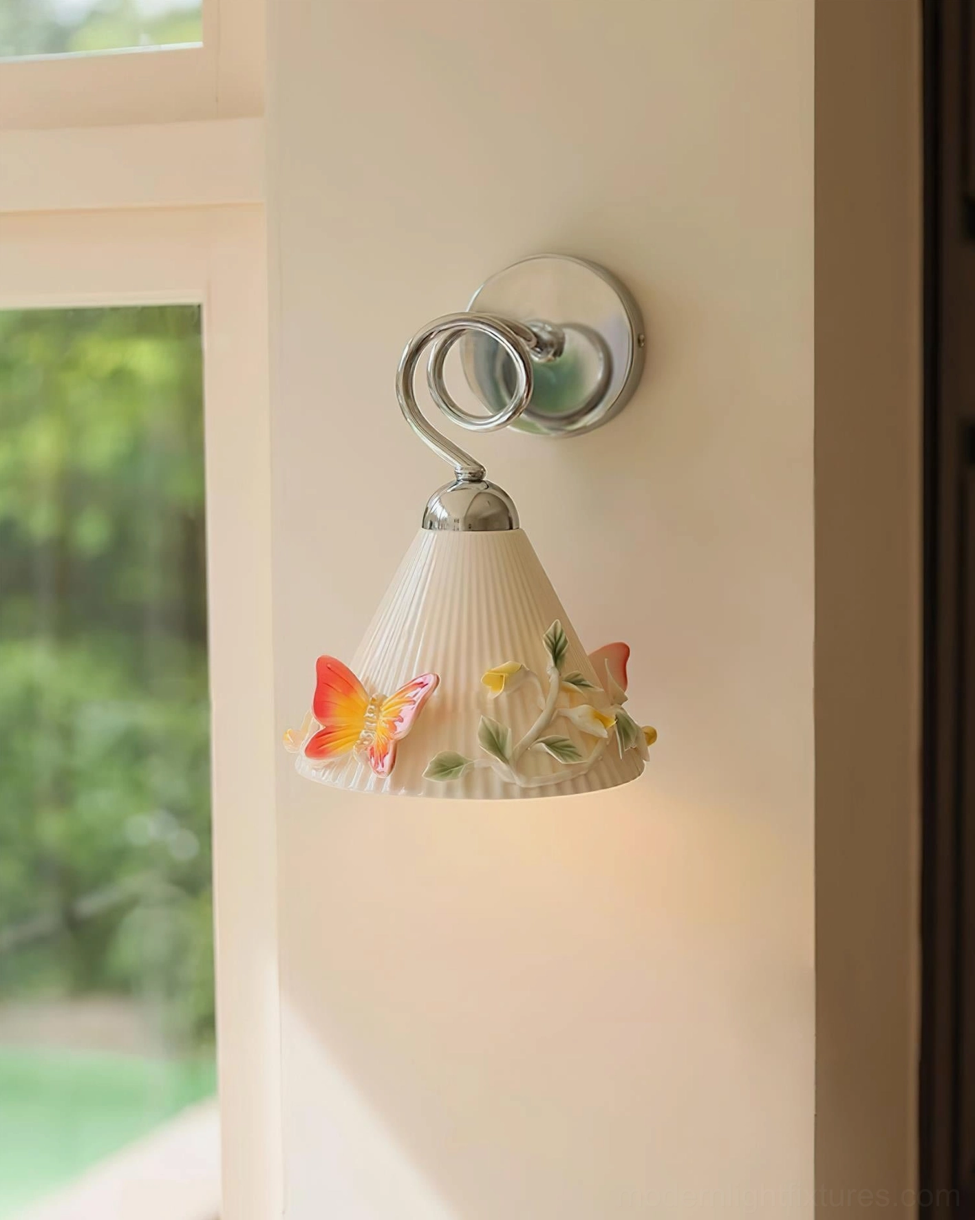 Hand-painted ceramic wall sconce front three-quarter perspective showing polished chrome curved lamp arm with embossed flowers and butterfly gradient details