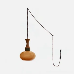 Chara plug-in pendant light with amber glass shade, wood cap, and braided black cord - front studio view