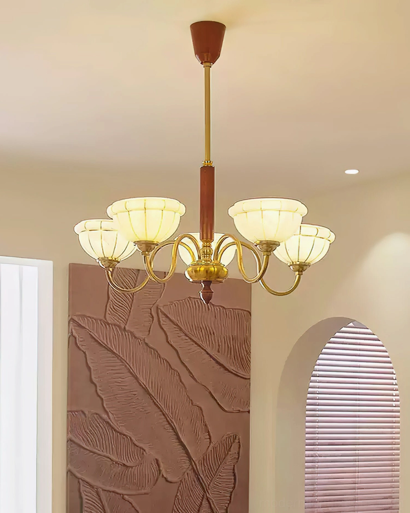 Illuminated Charlie chandelier with warm glowing frosted glass shades over mid-century modern dining setup