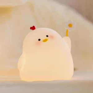 Lit chicken night light emitting warm yellow soft glow on cozy bedding