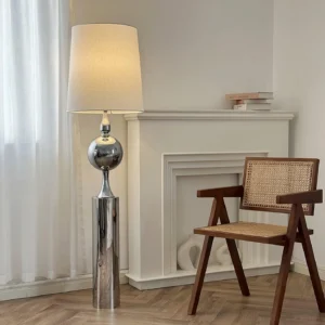 Chrome bubble floor lamp in contemporary living room with fireplace, sheer curtains, and neutral minimalist décor, demonstrating warm ambient lighting effect