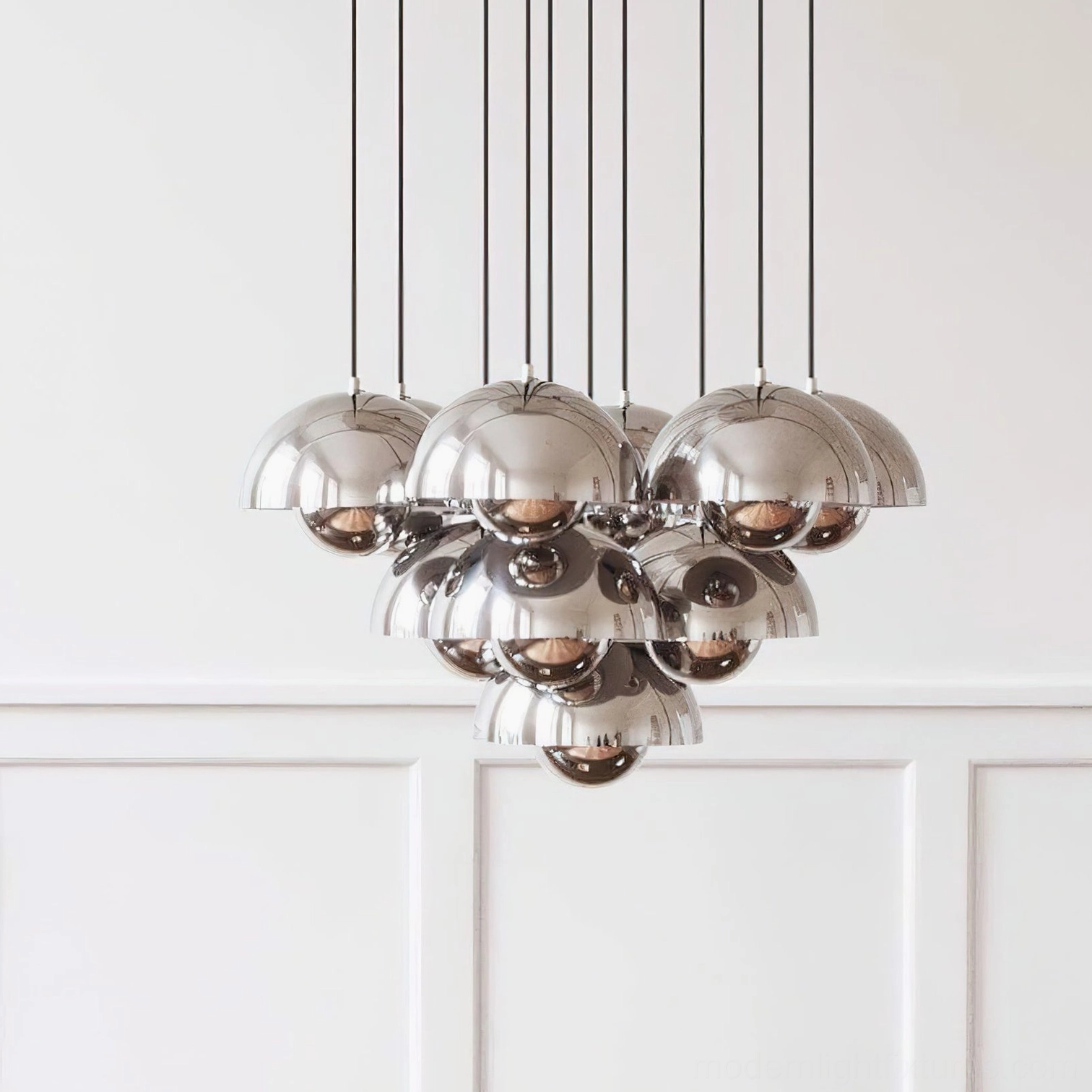 Contemporary chrome pendant chandelier close-up displaying polished metal hemispherical domes with clustered layered design against blank studio background