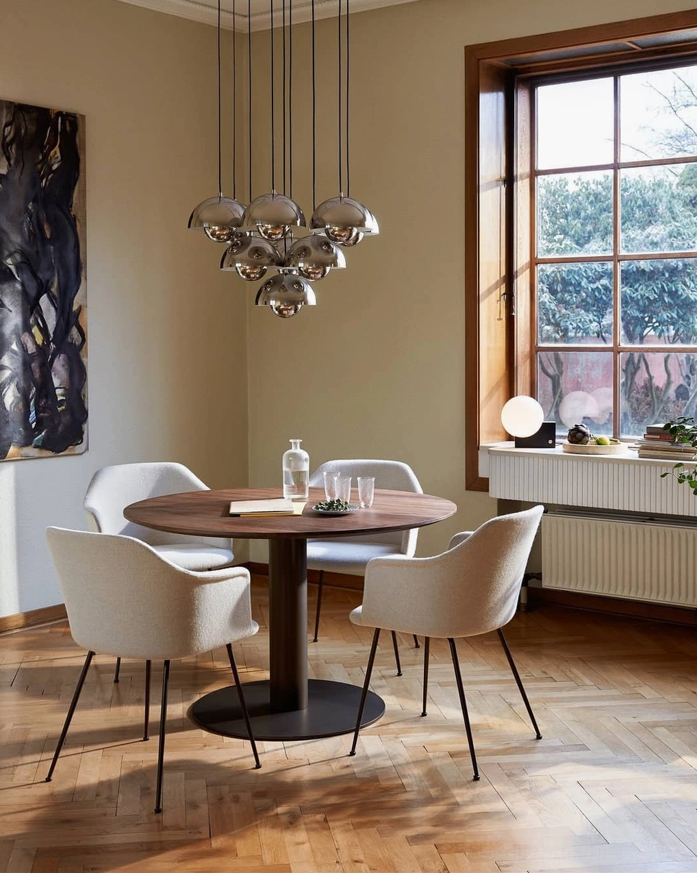 Contemporary dome pendant chandelier with chrome finish illuminating small round dining nook in modern minimalist home interior