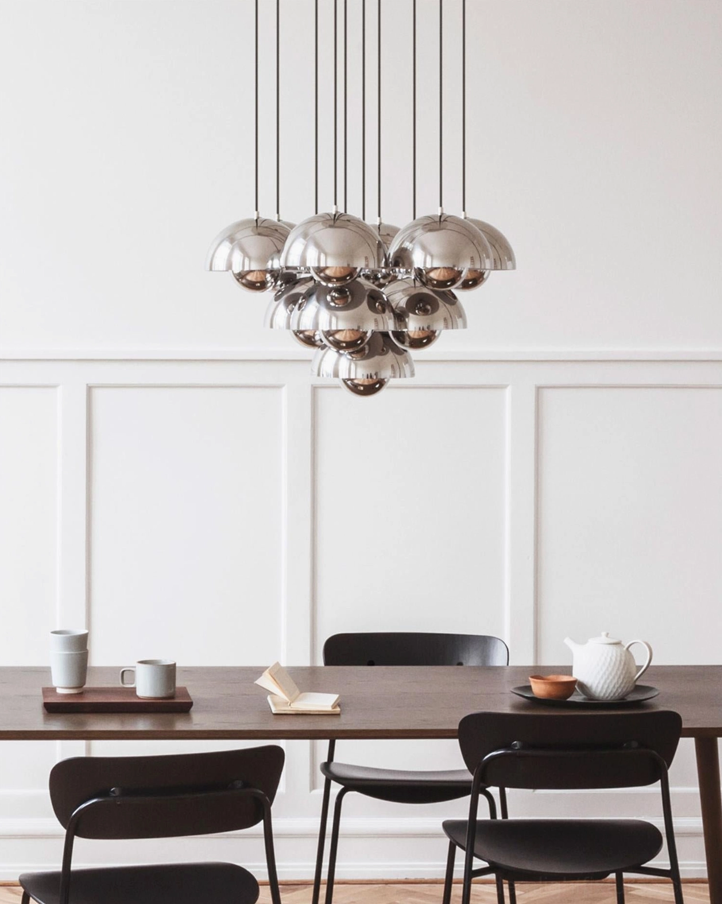 Modern chrome pendant chandelier installed in minimalist dining room at eye level, showing contemporary pendant fixture in residential interior design setting