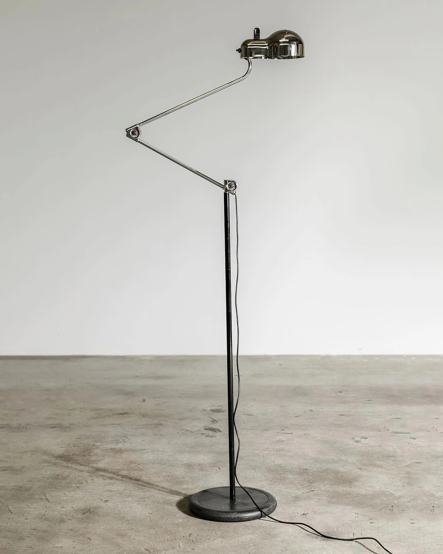 Chrome brushed metal swing arm floor lamp with polished finish shown in contemporary studio setting