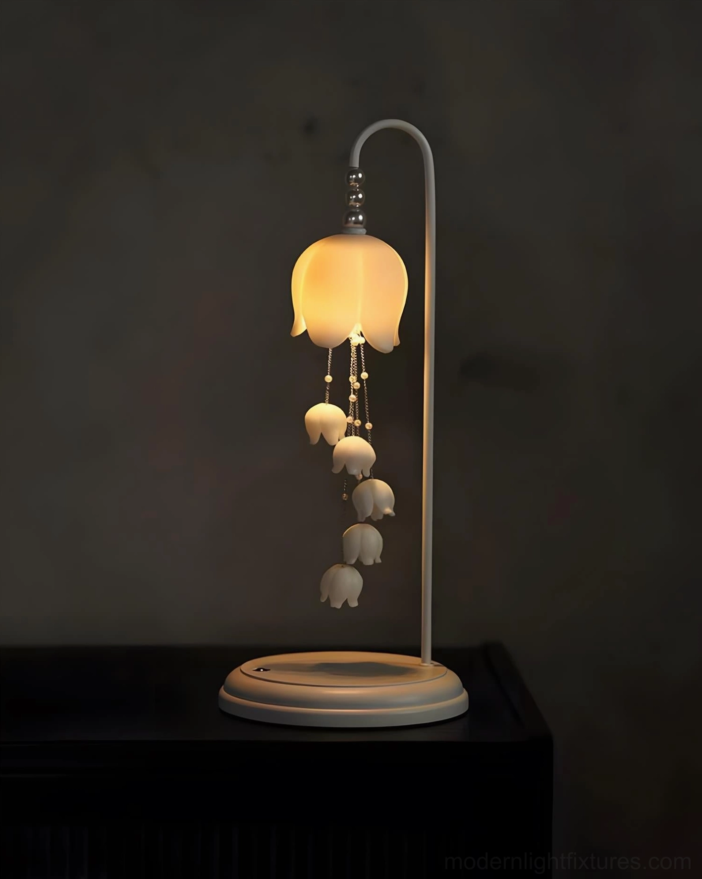Chyme Charge ceramic table lamp lit with warm yellow glow and dark furniture surroundings
