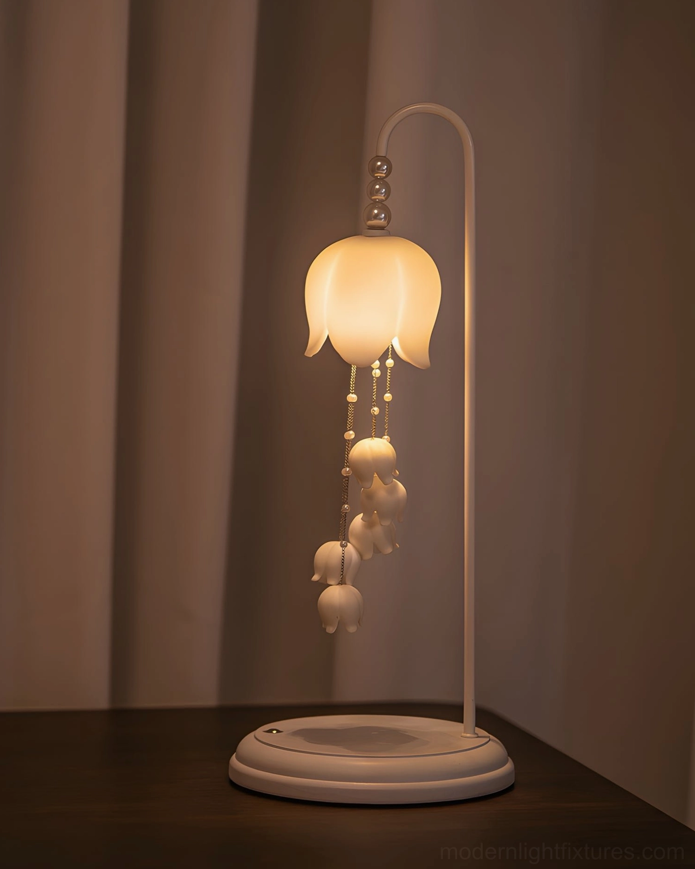Chyme Charge white table lamp illuminated on wooden side table with neutral curtains background