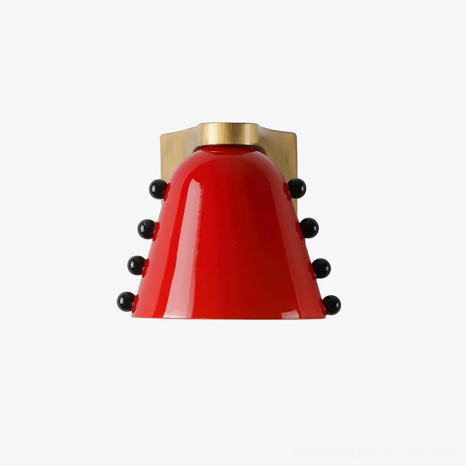 Red conical glass wall sconce with brushed brass mounting fixture and black spherical accent details in contemporary minimalist style