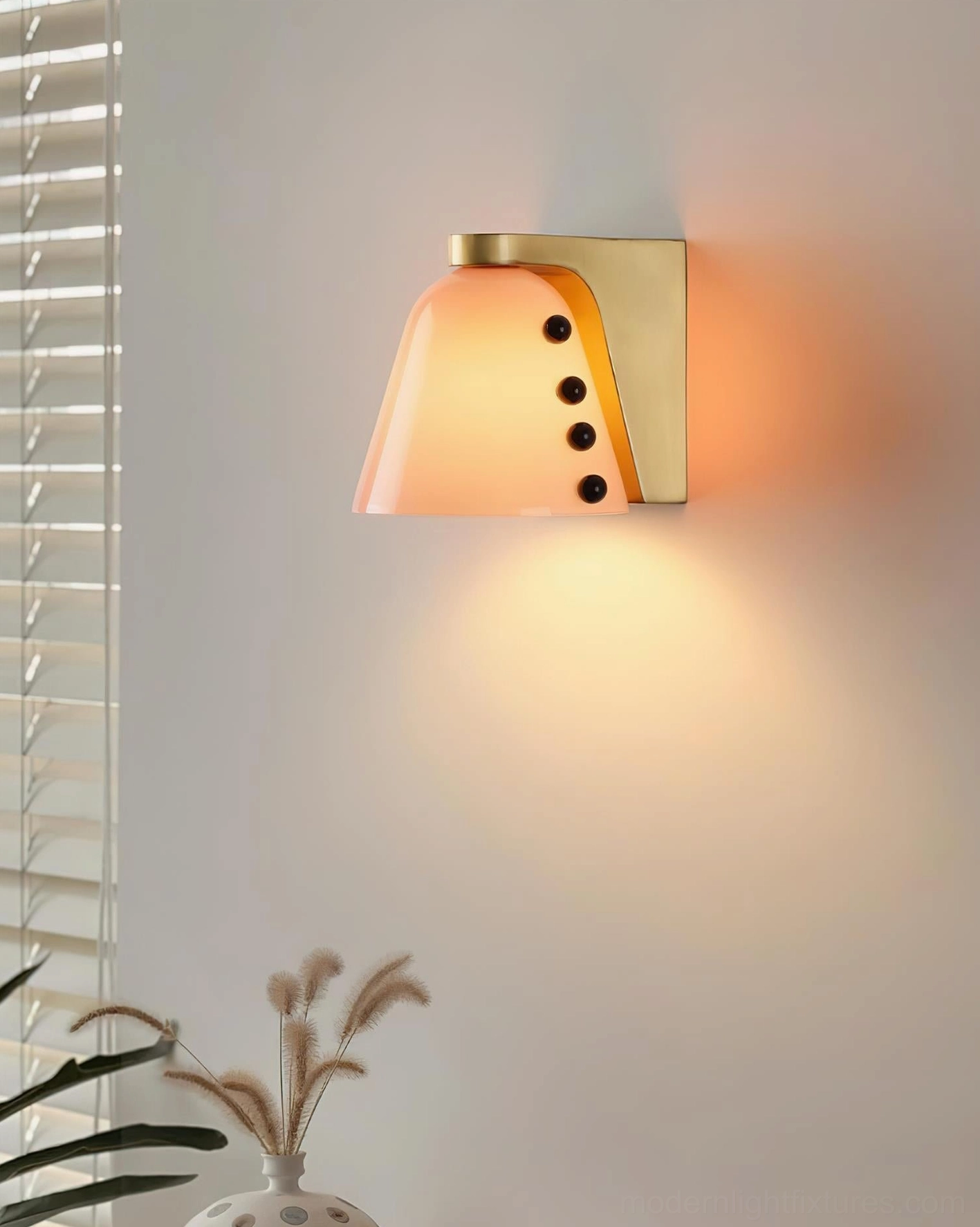 Light orange conical glass wall sconce with brass mounting base and black bead accents in modern home interior