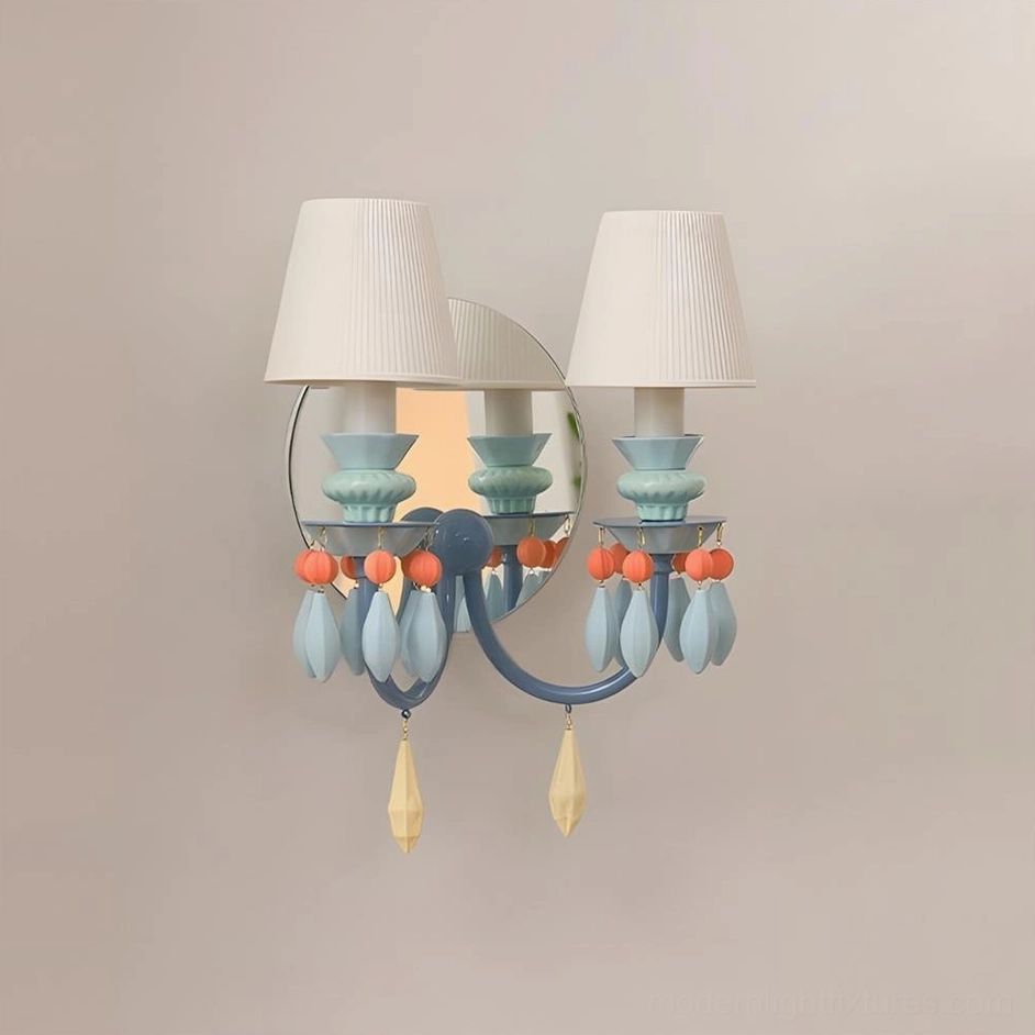 Cielora wall sconce in soft blue with teardrop-shaped ceramic beads, circular mirror backplate, and pleated fabric shades