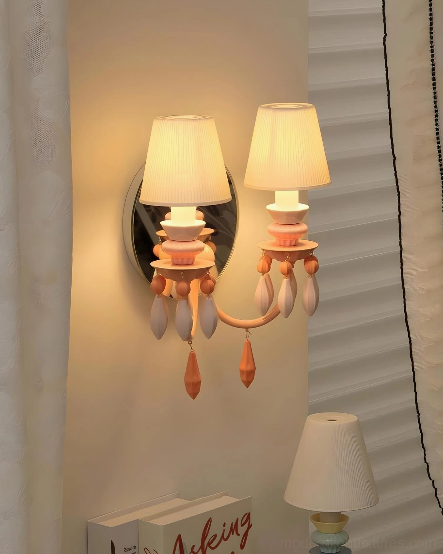 Cielora orange-toned dual-head wall sconce with warm amber glow illuminating teardrop ceramic beads in cozy bedroom ambiance