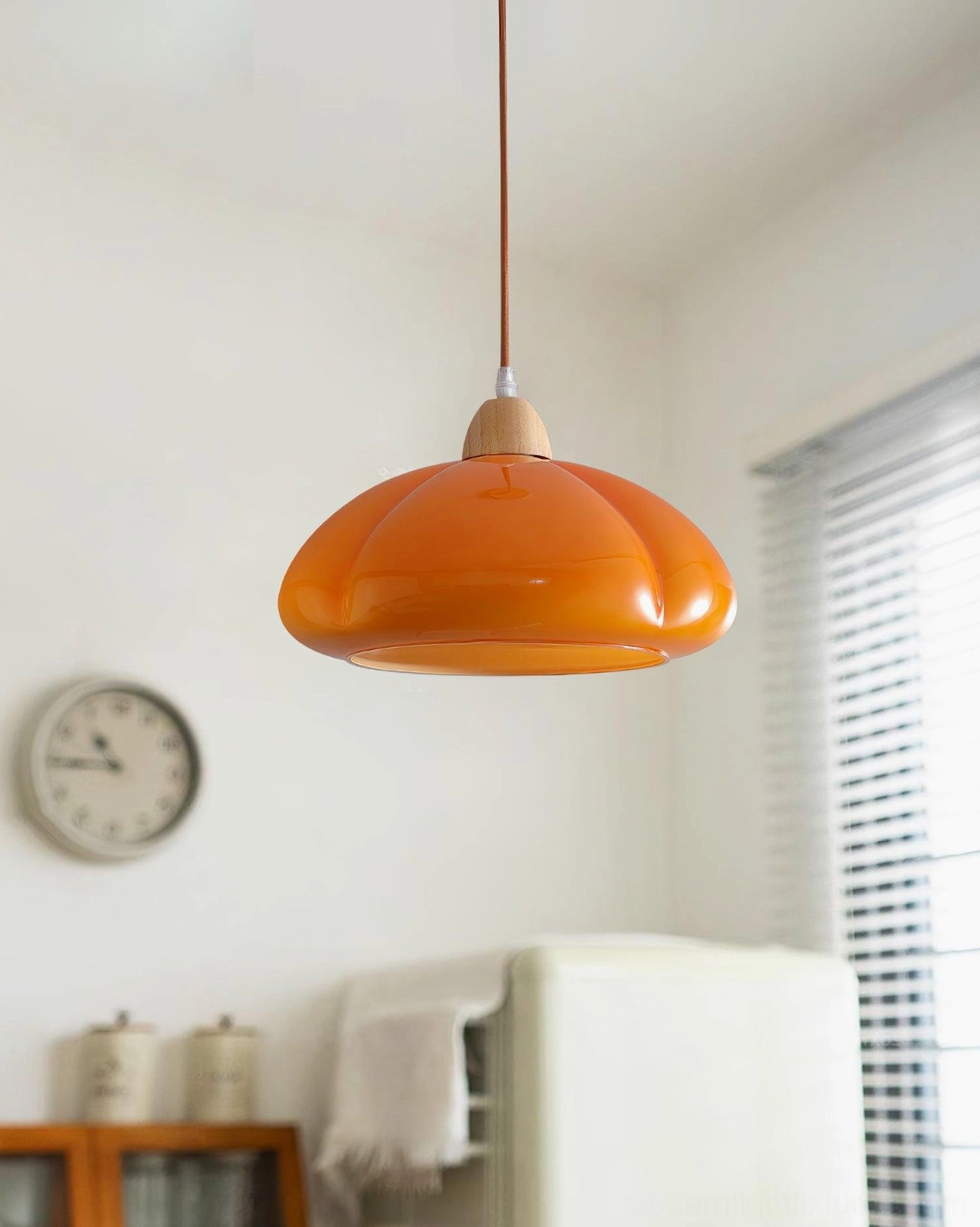 Cipola warm orange pumpkin pendant light installed in bright modern kitchen corner