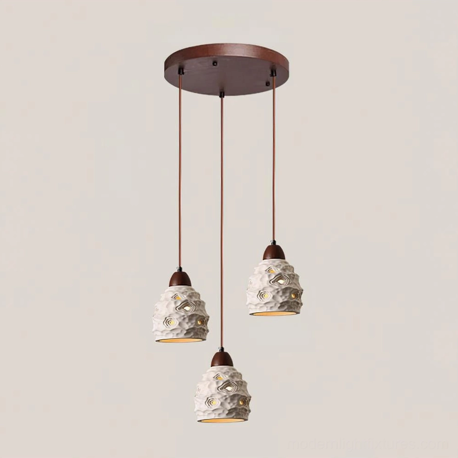 Circular 3-head ceramic pendant light arrangement in modern interior with perforated off-white shades