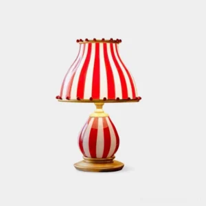 Red and white striped circus table lamp with pom-pom accents and gold metal base, front view studio shot