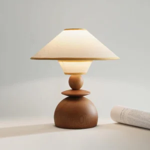 Beige fabric dome table lamp with warm walnut wood base illuminated in styled interior setting