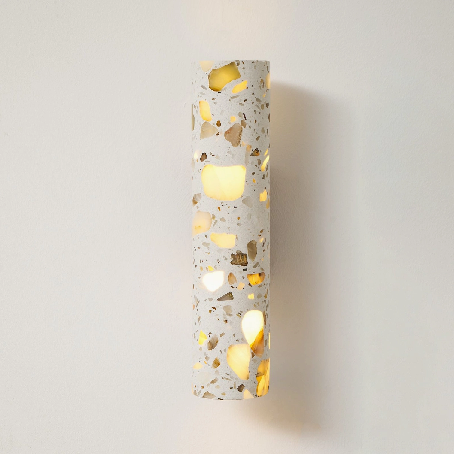 Modern cylindrical terrazzo wall lamp shade showing light diffusion through natural stone material