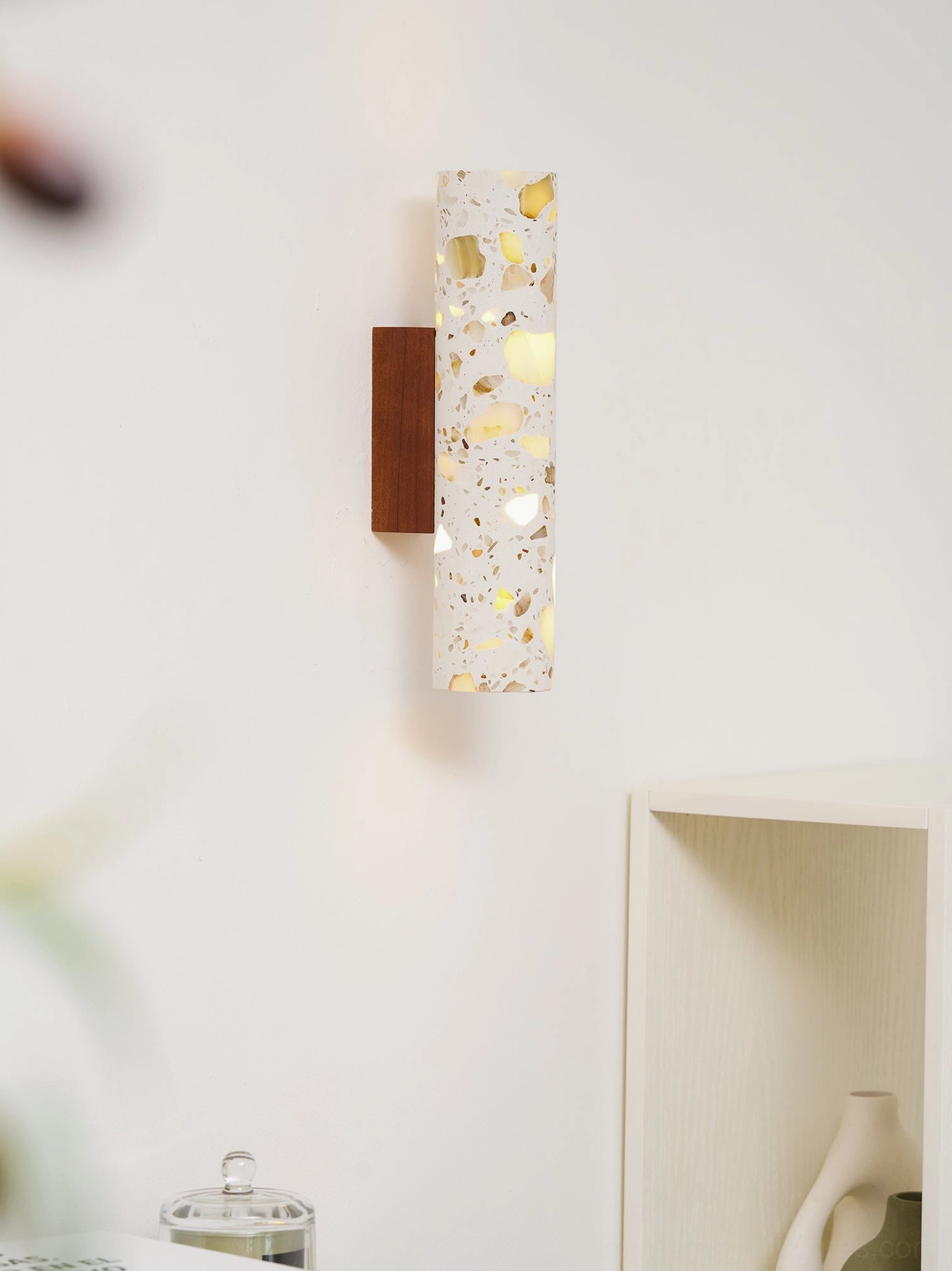 Terrazzo wall sconce installed in residential interior corner with warm illumination and gold flecked stone detail