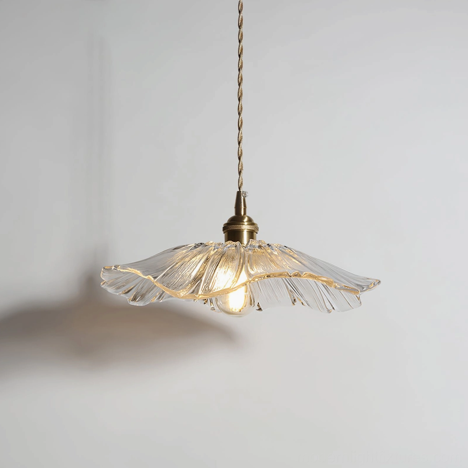Clear glass flower pendant light with transparent petal shade and glowing bulb bottom view