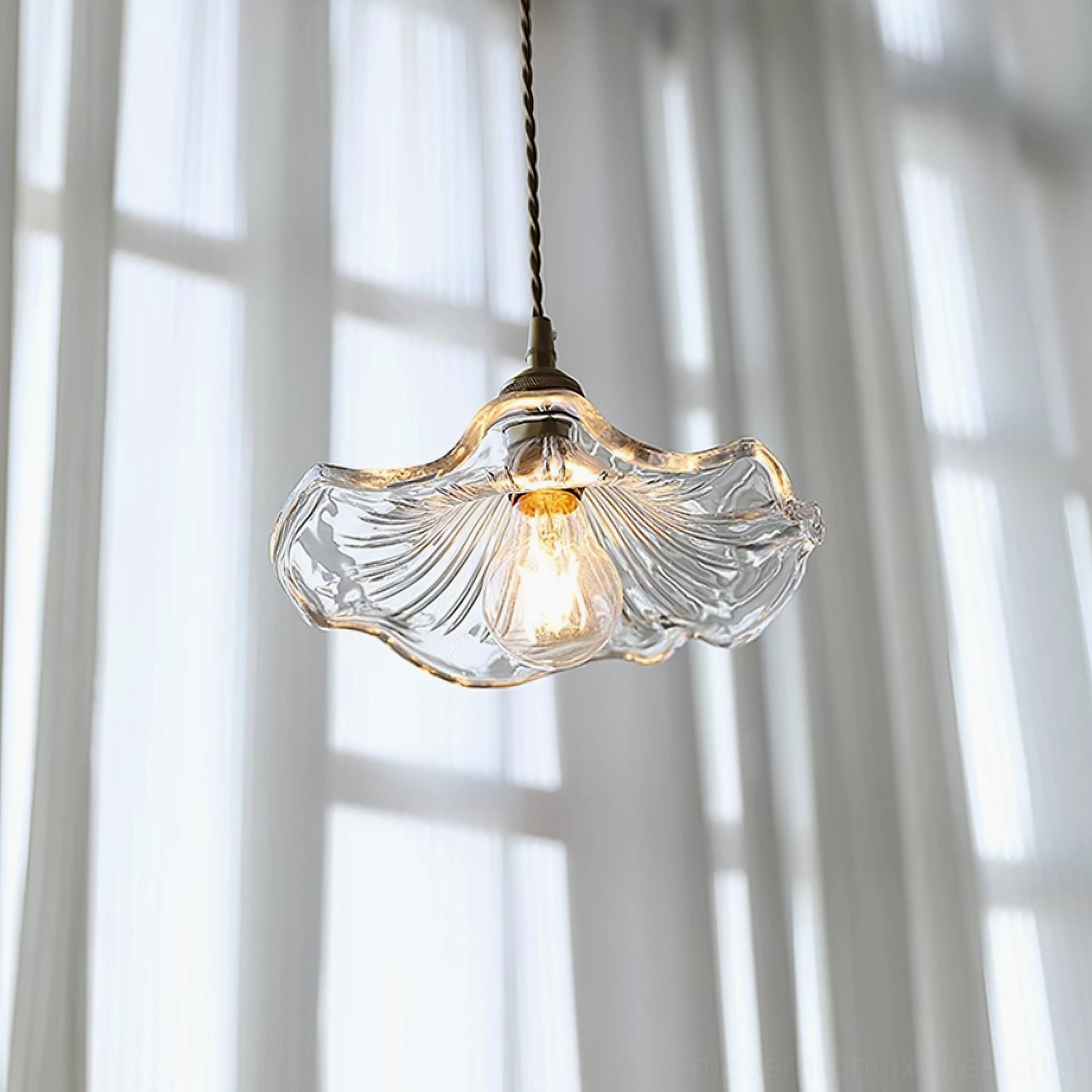 Clear flower glass pendant light hanging in window setting with sheer curtains and warm ambient glow