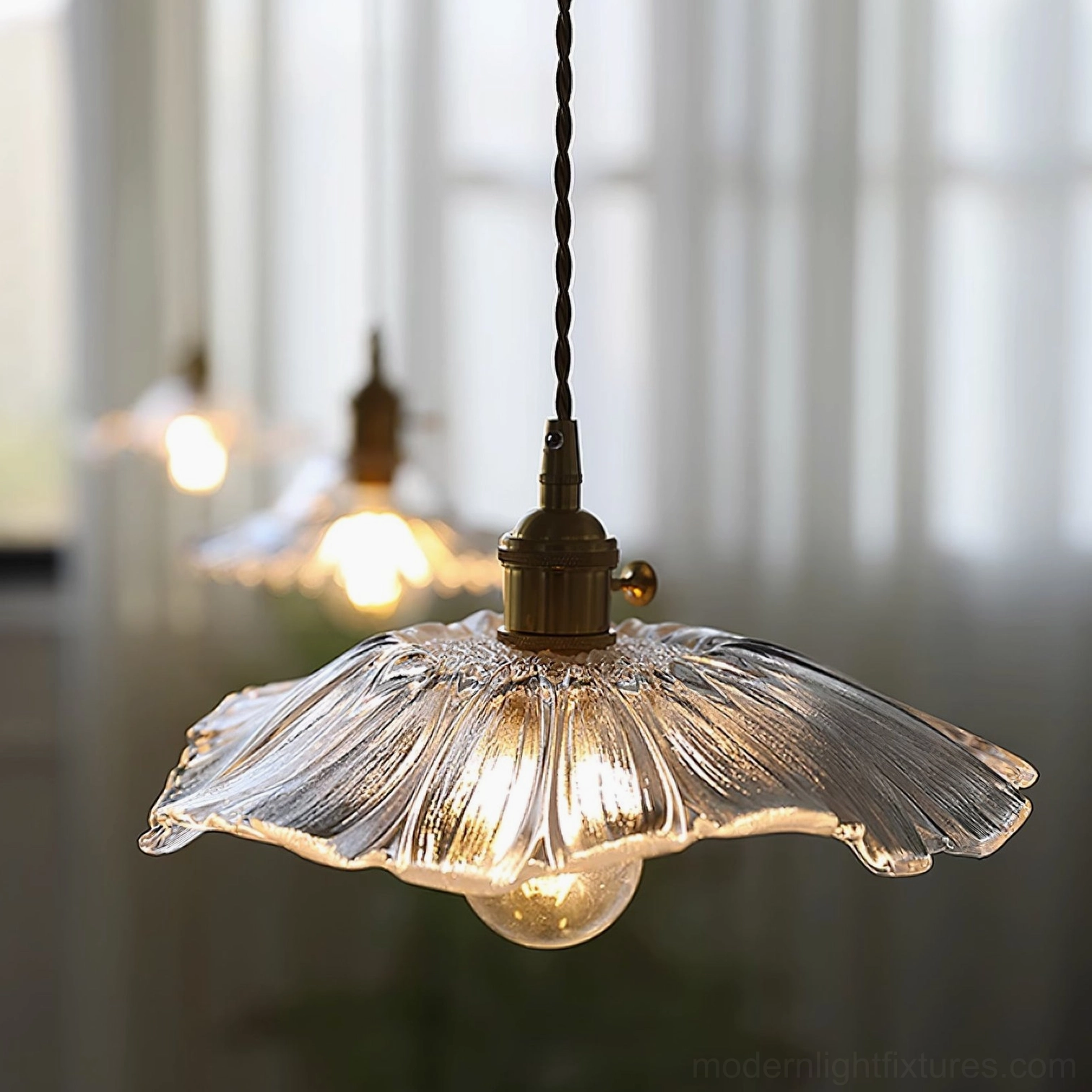 Close-up of clear glass petal pendant light with textured shade and black twisted cord in living room