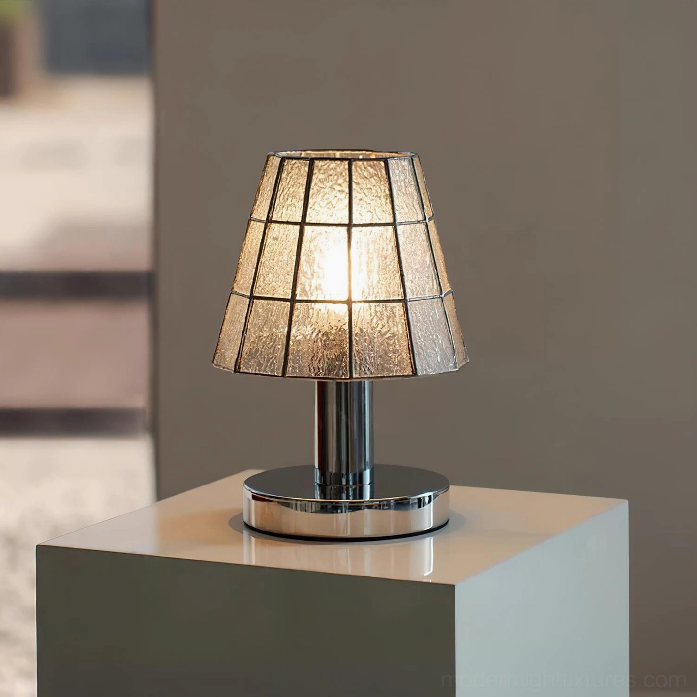 Crystal clear stained glass geometric table lamp highlighting chrome base and minimalist contemporary aesthetic