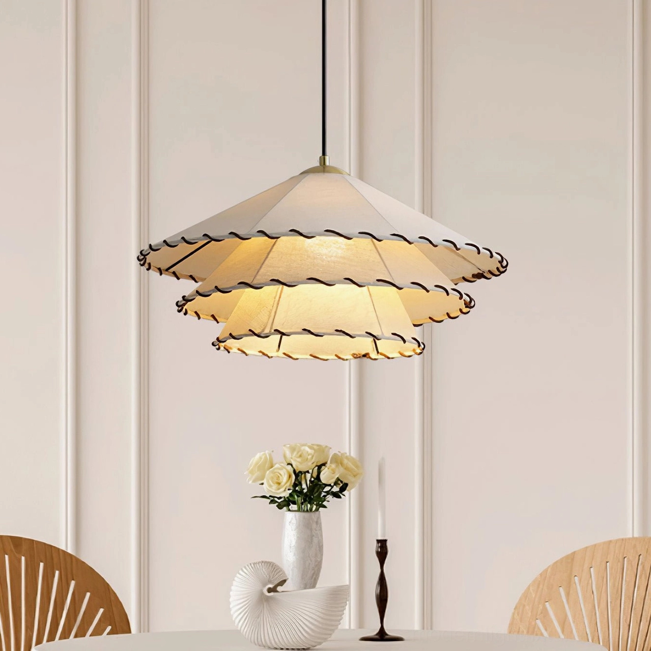 Close-up view of double-layer ruffled fabric pendant light above minimalist dining table with botanical decor