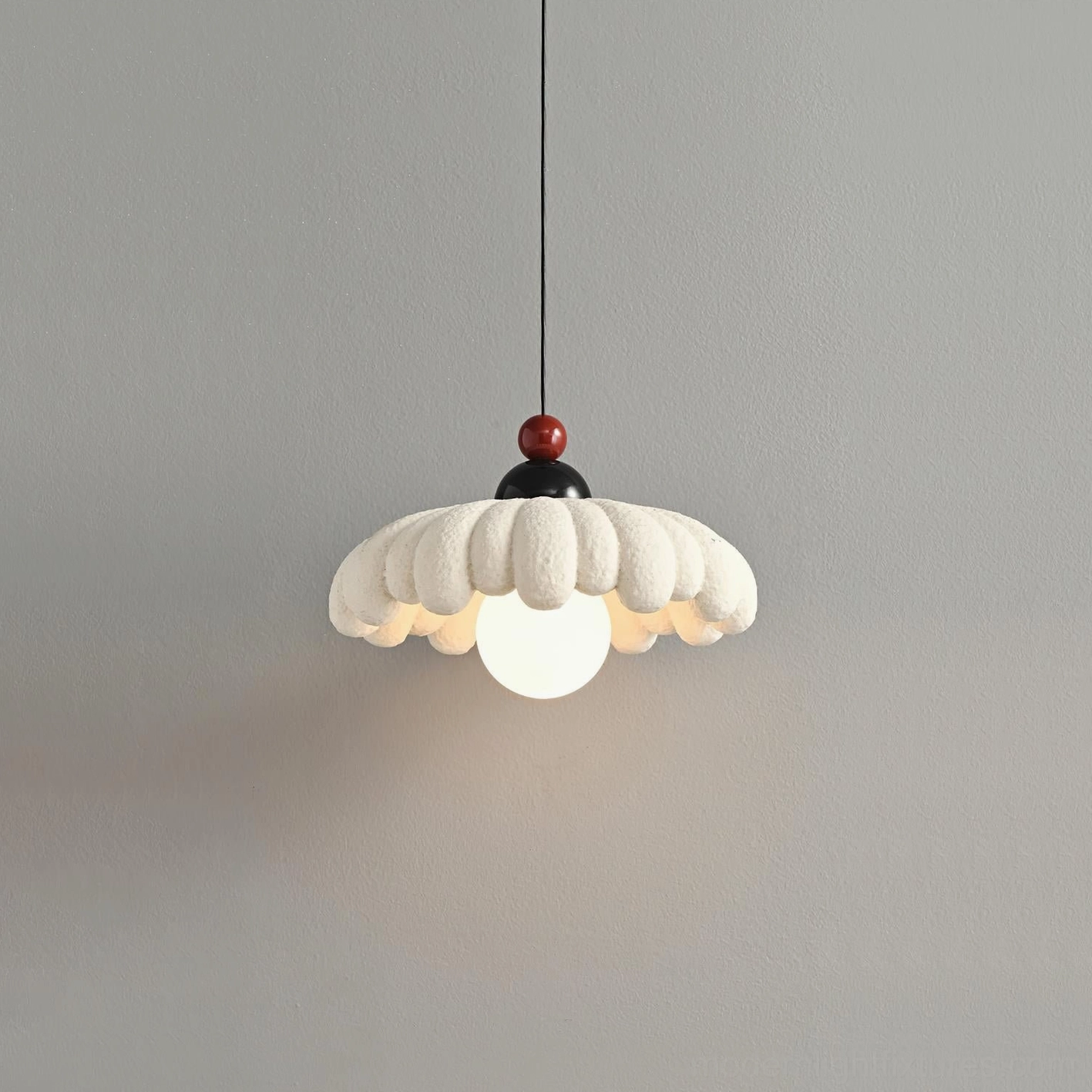 Cloudet sculptural pendant lamp with flower-shaped scalloped shade and glowing G9 bulb, angled view on gray backdrop