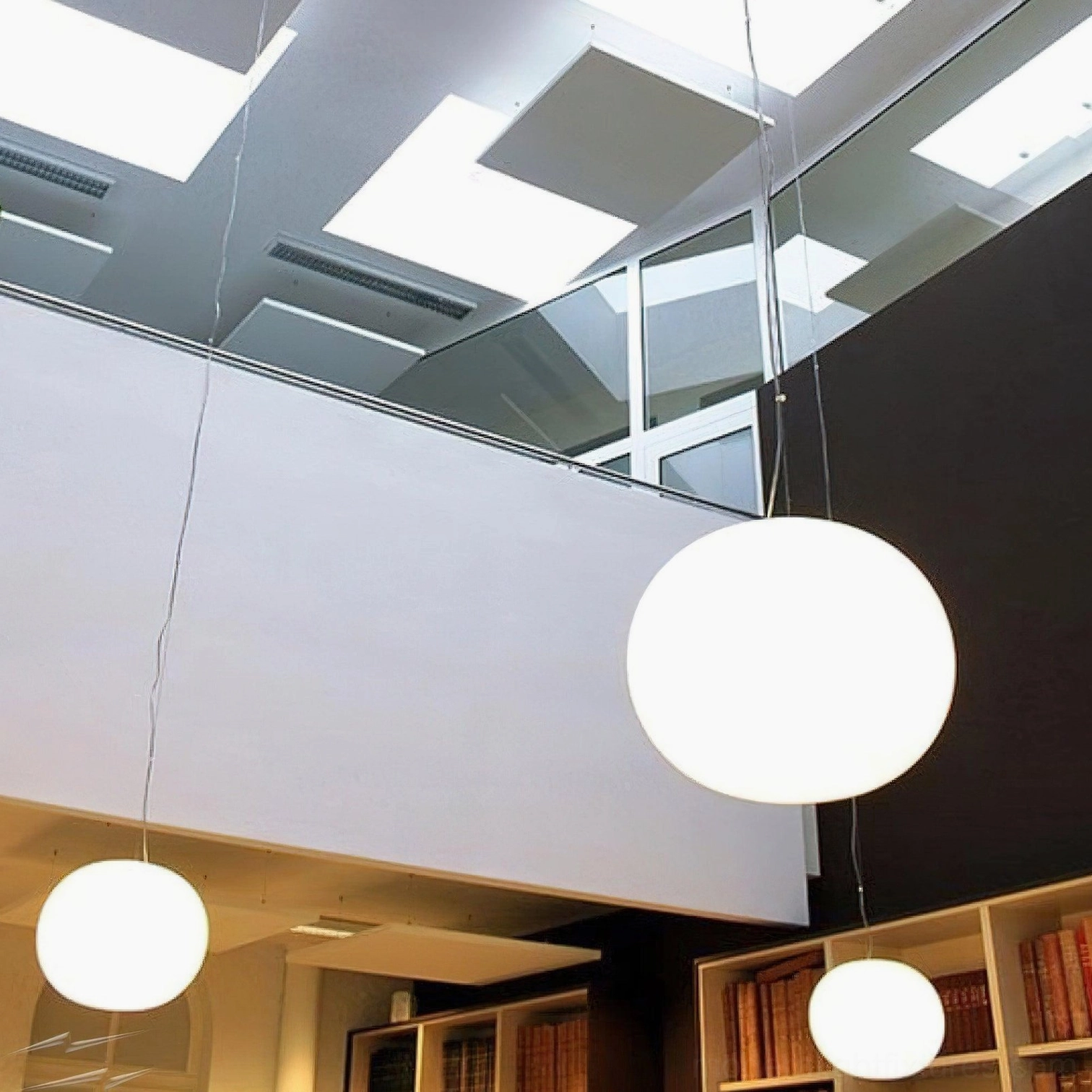 Multiple frosted glass sphere pendant lights clustered in modern duplex loft - three white pendant fixtures in contemporary minimalist space