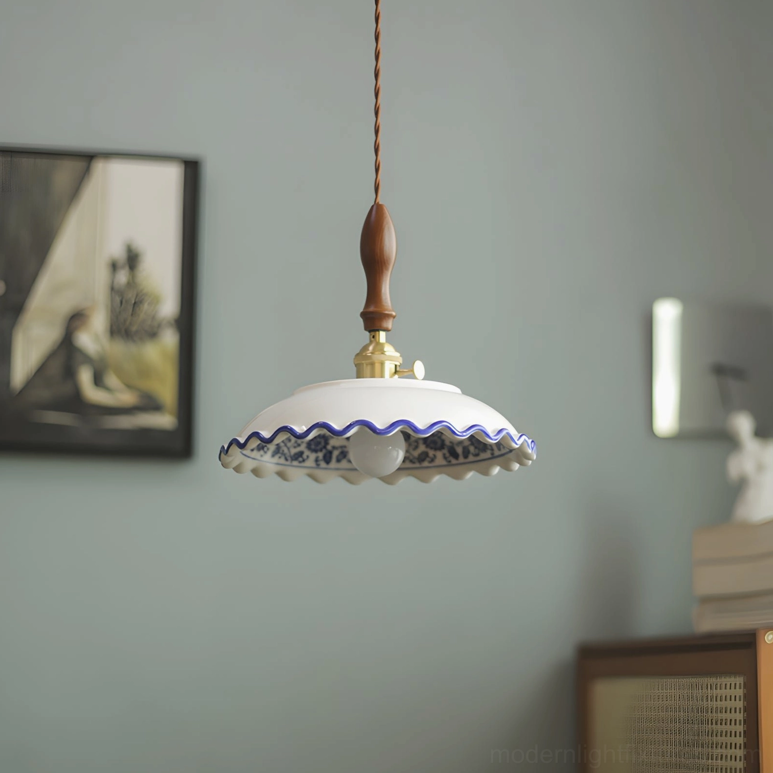 Low-angle close-up of Cobalisse porcelain pendant showing ruffled wavy scalloped rim, hand-painted cobalt blue motifs, and twisted braided cord