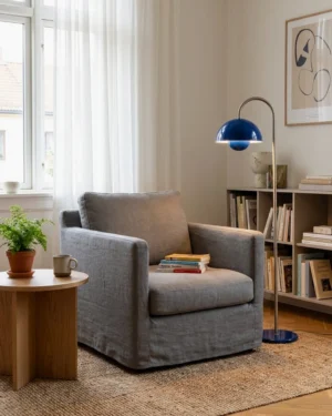 Navy arc floor lamp illuminating cozy reading nook with grey armchair and wooden side table