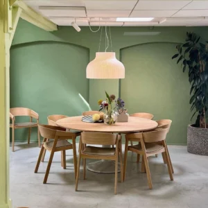 Contemporary pendant light installed above wooden dining table in modern dining room with green accent wall