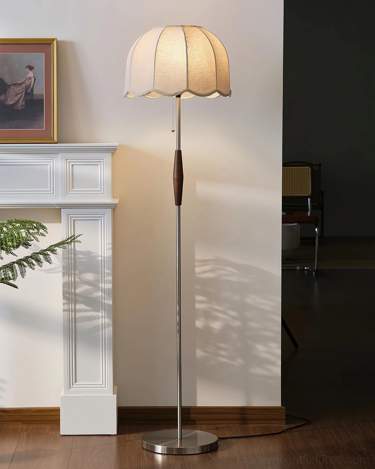 Colette floor lamp illuminated, left-side view in living room with fireplace mantel and framed artwork, ambient lighting